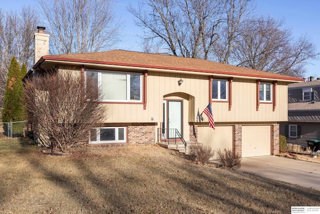 raised ranch featuring a garage, brick siding, fence, concrete driveway, and a chimney