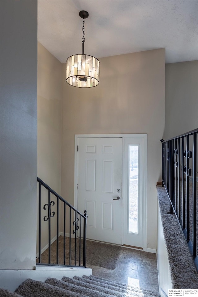 foyer entrance with an inviting chandelier, baseboards, a high ceiling, and stairway