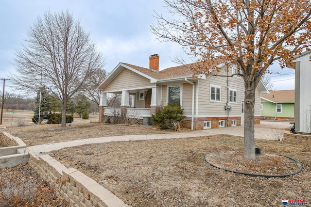 view of front of property with roof with shingles, a porch, and a chimney