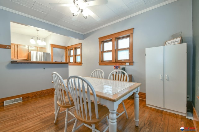 dining room with crown molding, visible vents, and wood finished floors