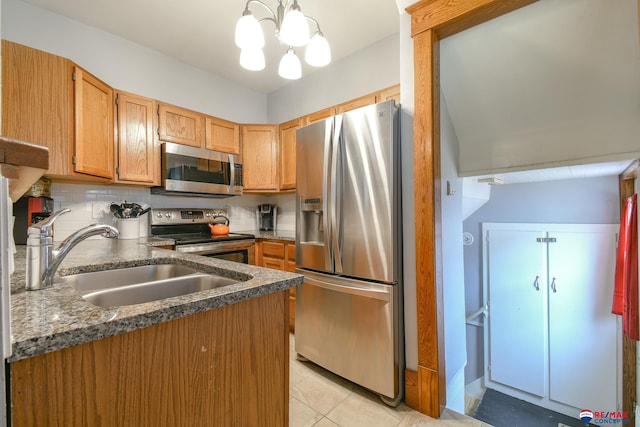 kitchen featuring tasteful backsplash, dark countertops, appliances with stainless steel finishes, a sink, and light tile patterned flooring