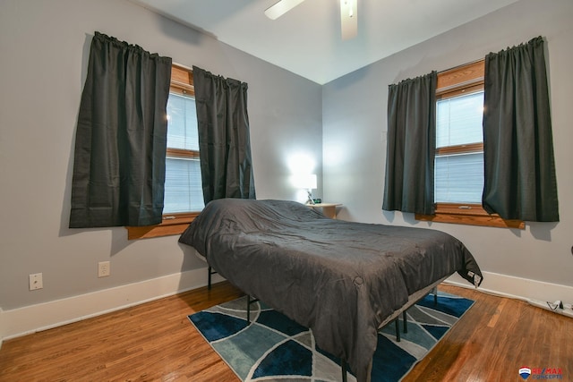 bedroom with ceiling fan, wood finished floors, lofted ceiling, and baseboards