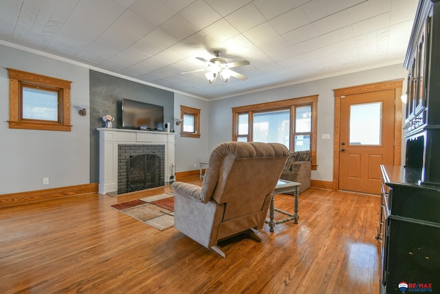 living room with crown molding, a fireplace, and light wood-style flooring