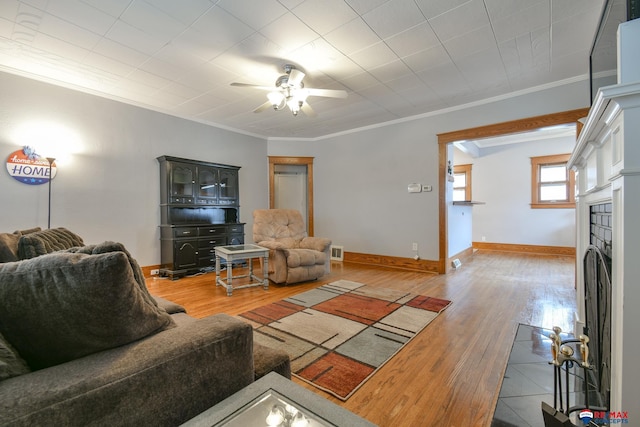 living room with a fireplace with flush hearth, ornamental molding, wood finished floors, and baseboards