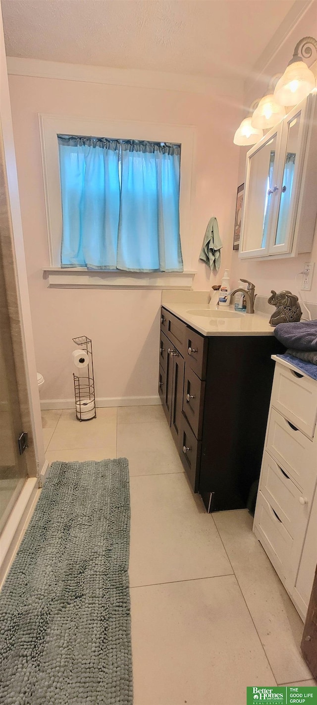 bathroom featuring baseboards, a stall shower, vanity, and tile patterned floors