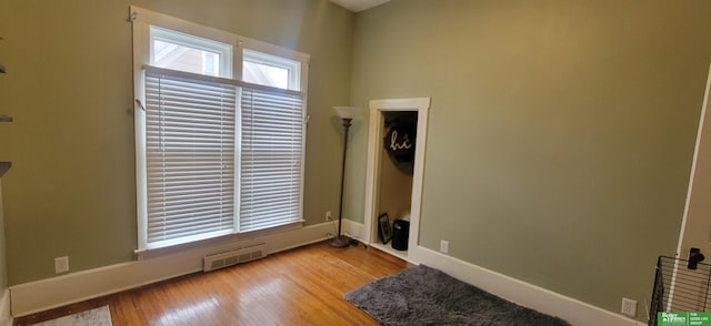 spare room featuring wood finished floors, visible vents, and baseboards