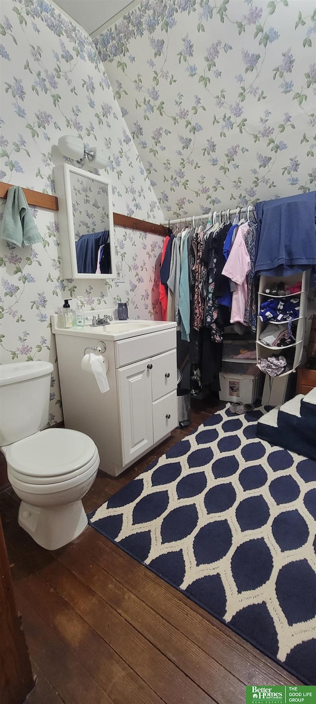 bathroom with toilet, wallpapered walls, hardwood / wood-style floors, and vanity