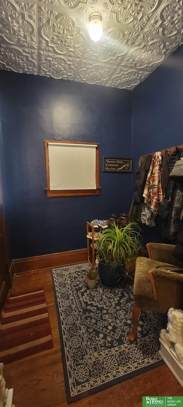 living area with wood finished floors, an ornate ceiling, and baseboards