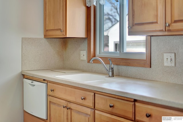 kitchen featuring a sink, dishwasher, light brown cabinetry, and light countertops