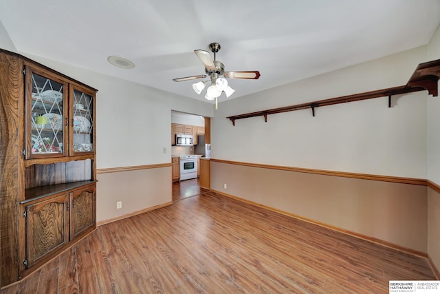 empty room featuring light wood finished floors, visible vents, ceiling fan, and baseboards