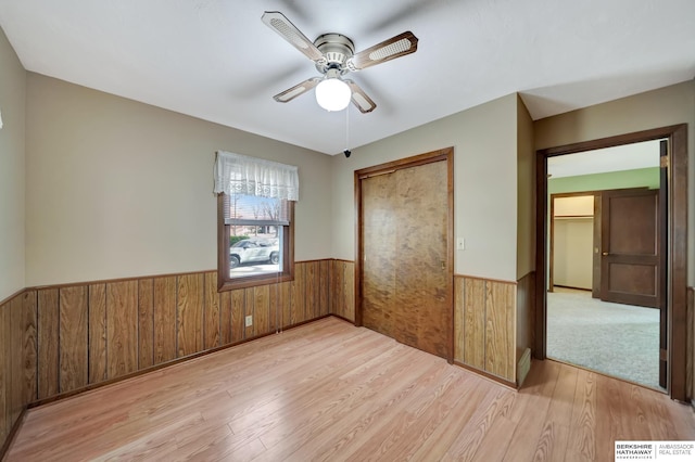 unfurnished bedroom with wood finished floors, a wainscoted wall, a closet, and wood walls