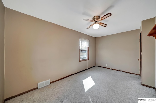 spare room with visible vents, baseboards, light colored carpet, and a ceiling fan