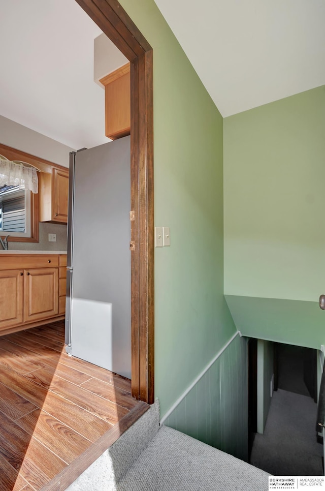 stairs featuring wood finished floors and wainscoting