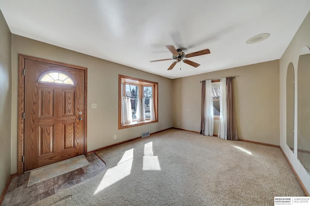 foyer entrance featuring arched walkways, visible vents, carpet floors, and baseboards