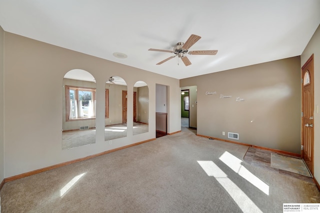 spare room with arched walkways, visible vents, baseboards, and ceiling fan