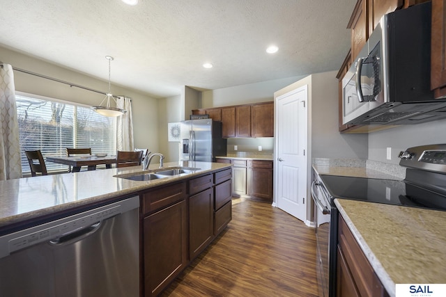 kitchen with a textured ceiling, a sink, appliances with stainless steel finishes, dark wood-style floors, and decorative light fixtures