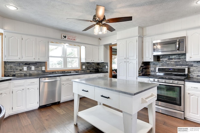 kitchen with appliances with stainless steel finishes, dark countertops, white cabinets, and dark wood-style floors