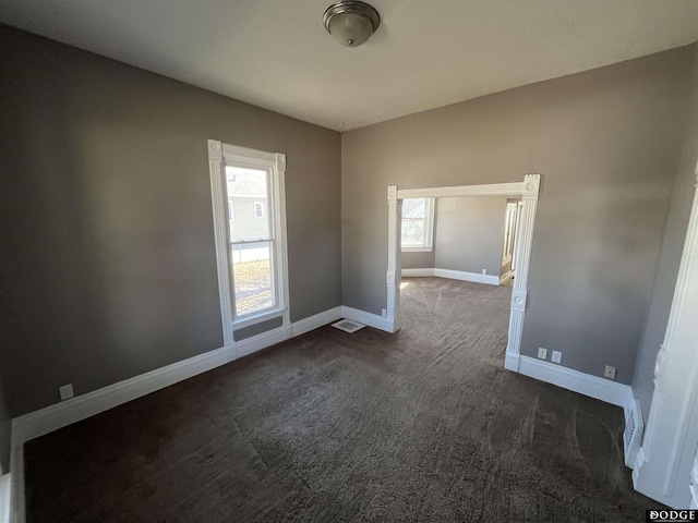 spare room with dark colored carpet and baseboards