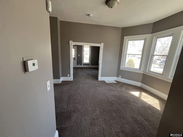 empty room with dark colored carpet and baseboards