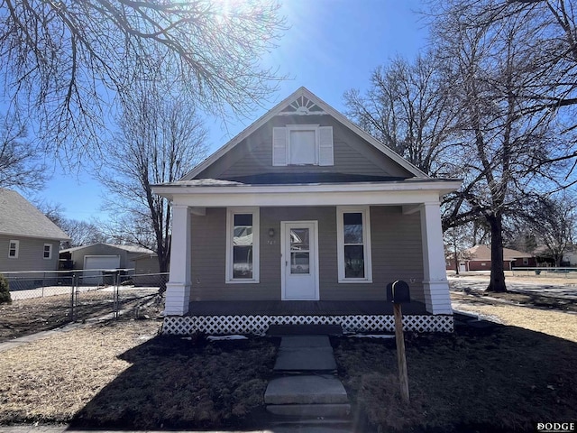 bungalow-style house featuring a porch, an outbuilding, fence, and a detached garage