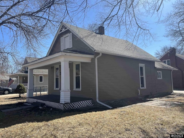 view of property exterior with covered porch and a chimney