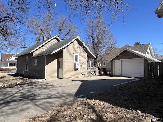 view of side of property with driveway, a chimney, and fence