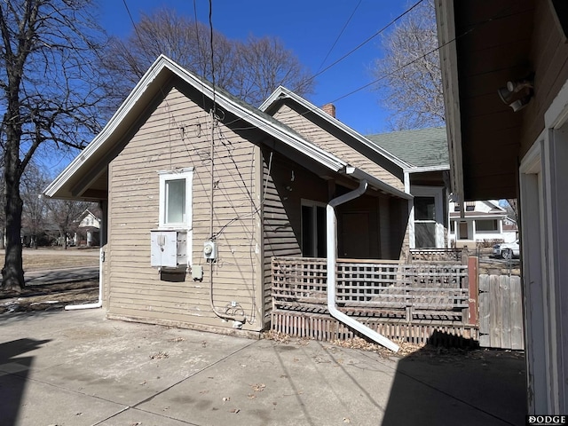 view of side of home featuring a patio area and roof with shingles