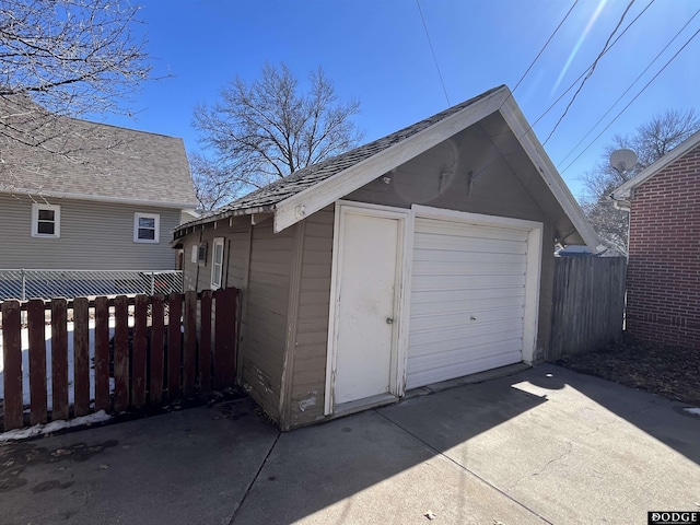 view of outbuilding featuring fence, concrete driveway, and an outdoor structure