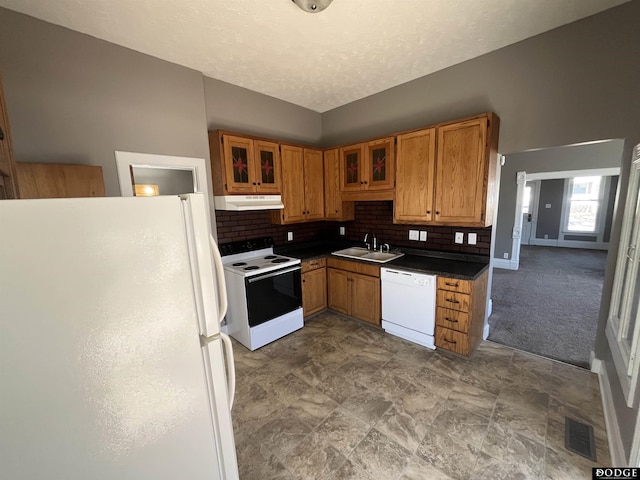 kitchen with dark countertops, visible vents, a sink, white appliances, and under cabinet range hood