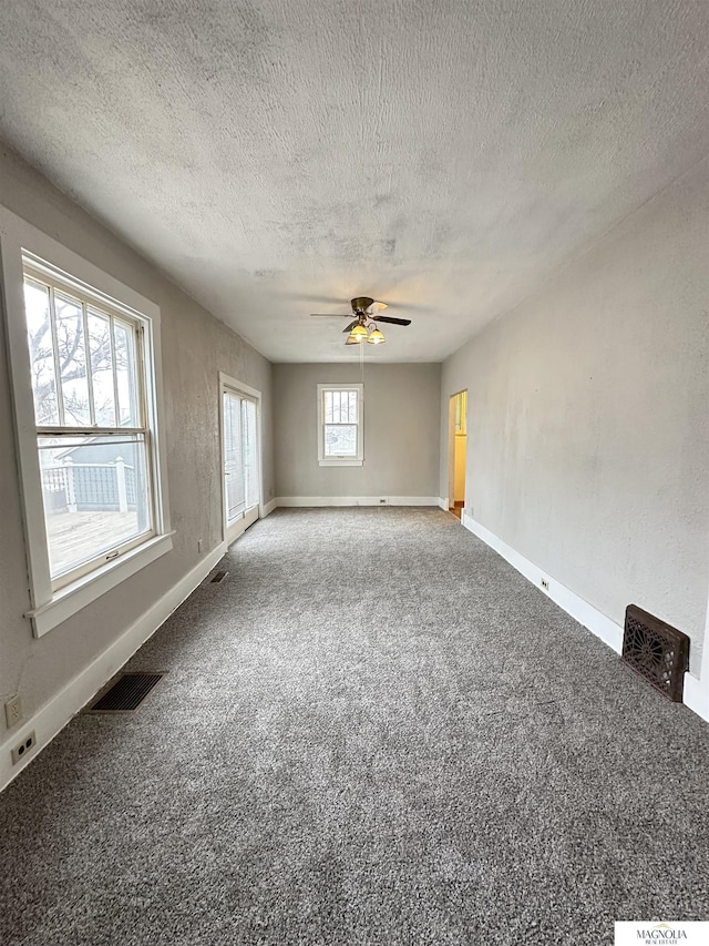 carpeted spare room with visible vents, ceiling fan, a textured ceiling, and baseboards