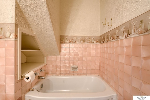 bathroom with a bath and a textured wall