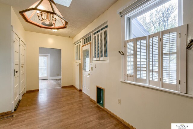 interior space with a healthy amount of sunlight, a textured ceiling, visible vents, and wood finished floors