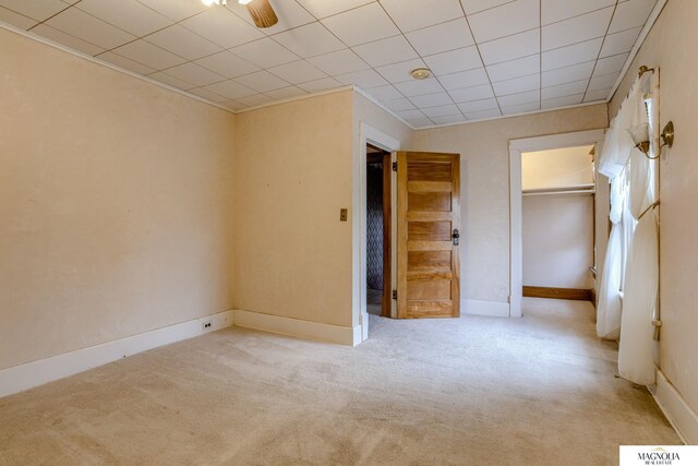 carpeted empty room featuring a drop ceiling and baseboards