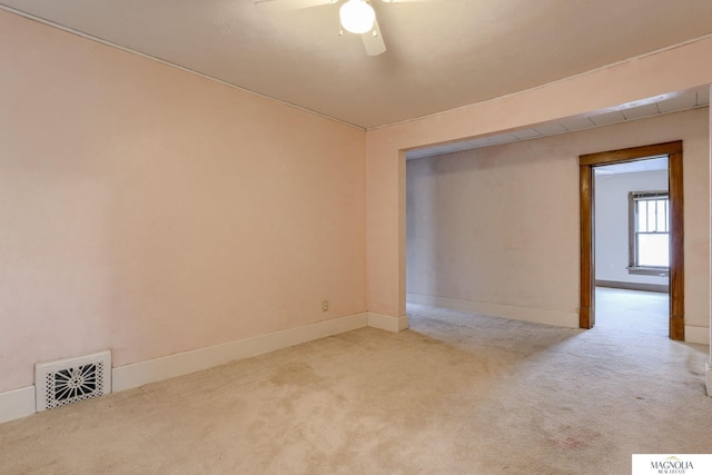 carpeted empty room featuring a ceiling fan, visible vents, and baseboards