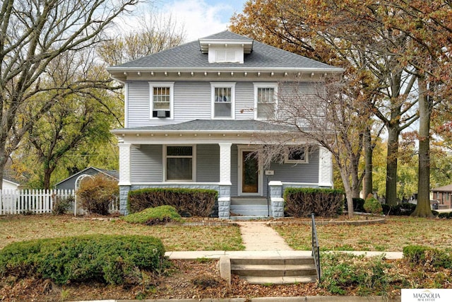 american foursquare style home with fence, a porch, and roof with shingles