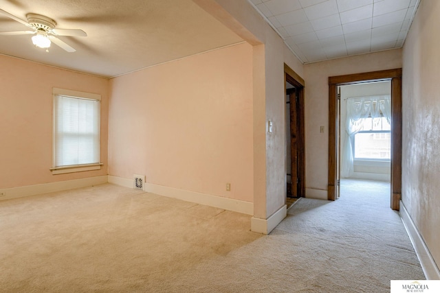 carpeted empty room featuring a ceiling fan, visible vents, and baseboards