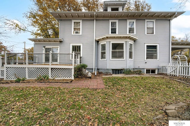 back of house featuring fence, a deck, and a lawn