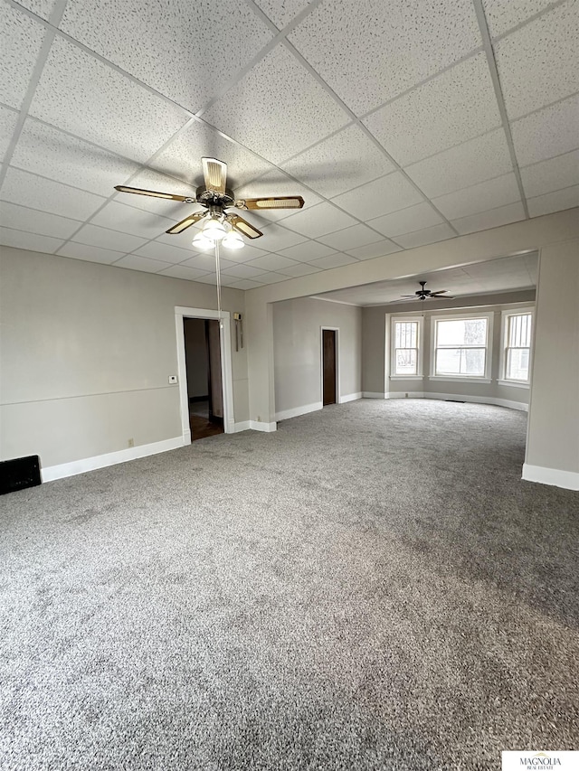 carpeted spare room with a paneled ceiling, ceiling fan, and baseboards