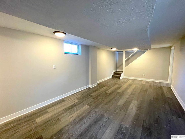 basement featuring a textured ceiling, stairway, wood finished floors, and baseboards