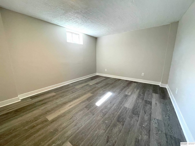 empty room featuring dark wood-style floors, baseboards, and a textured ceiling