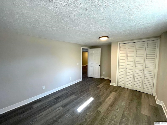 unfurnished bedroom with dark wood-style floors, a textured ceiling, and baseboards