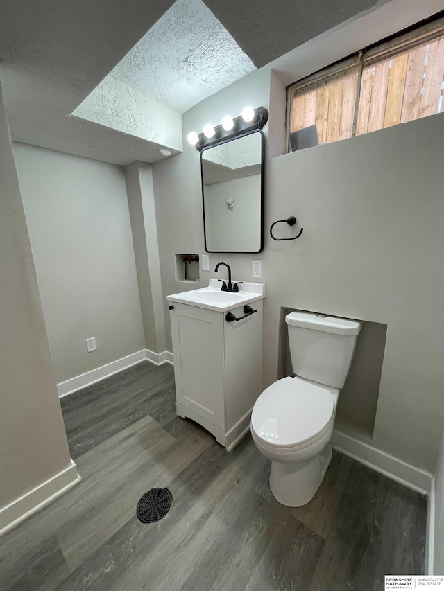 half bathroom featuring vanity, wood finished floors, toilet, and baseboards