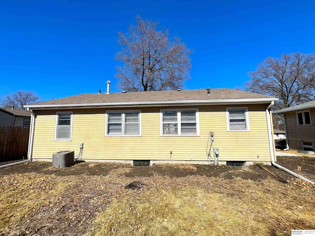 rear view of house featuring a shingled roof, cooling unit, and fence