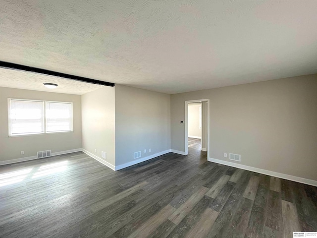 unfurnished room with dark wood-style floors, a textured ceiling, visible vents, and baseboards