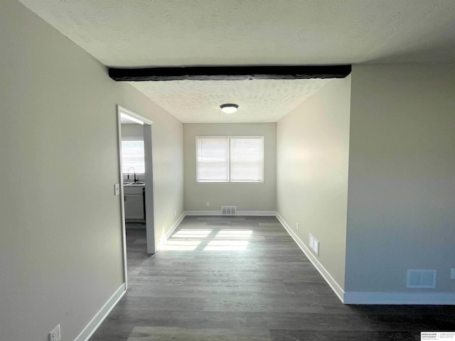 interior space with baseboards, visible vents, a textured ceiling, and wood finished floors