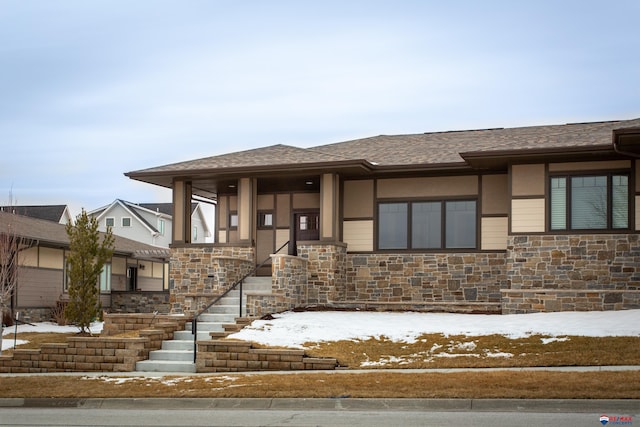 prairie-style house with stone siding, stucco siding, and roof with shingles