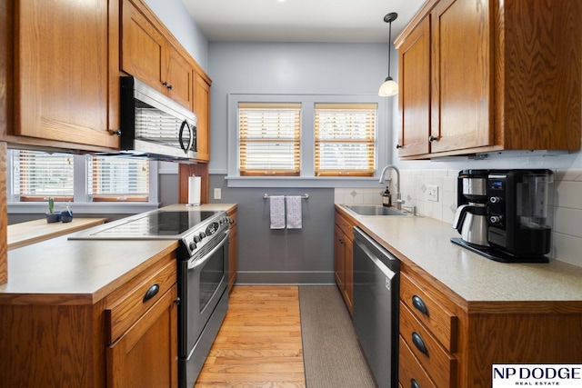 kitchen featuring brown cabinets, stainless steel appliances, and a sink