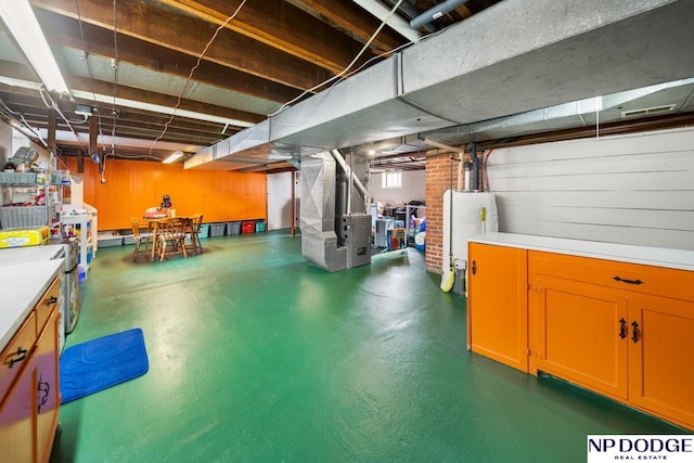 basement featuring wooden walls, heating unit, and water heater