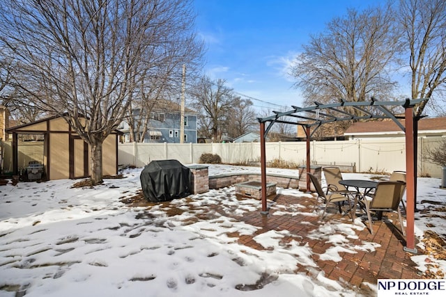 yard covered in snow with a patio, an outbuilding, a fenced backyard, and a pergola