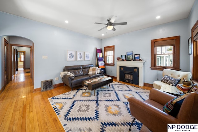 living area with recessed lighting, arched walkways, visible vents, and light wood finished floors